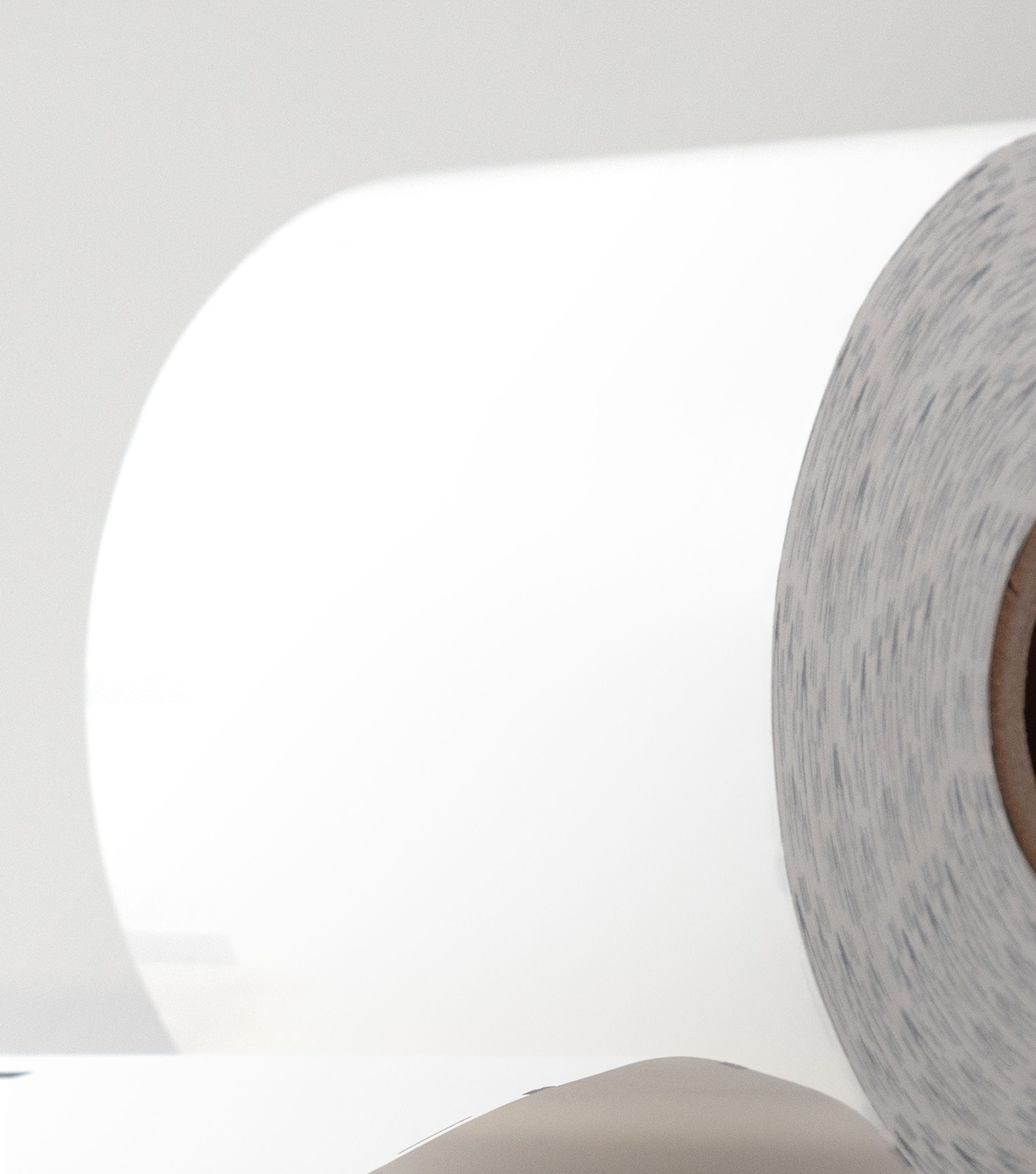 Close-up of a white paper roll's smooth curved surface and coiled edge, on a gray background
